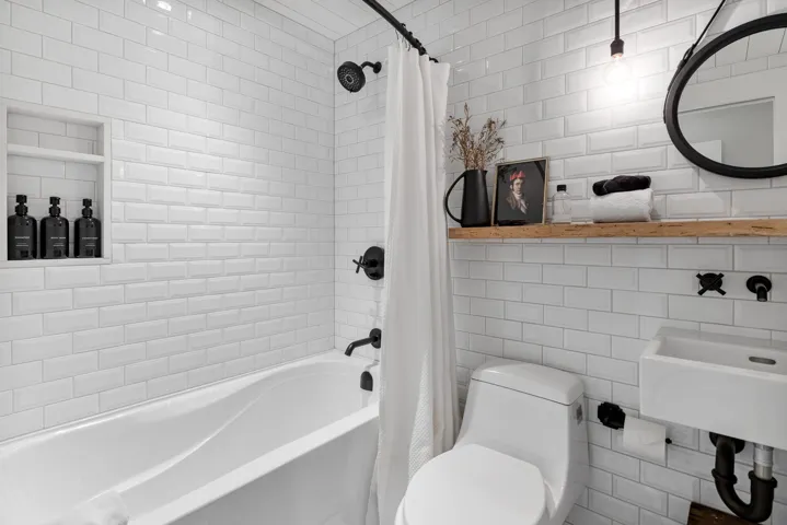 Bathroom with toilet, tile walls, and shower / tub combo with curtain
