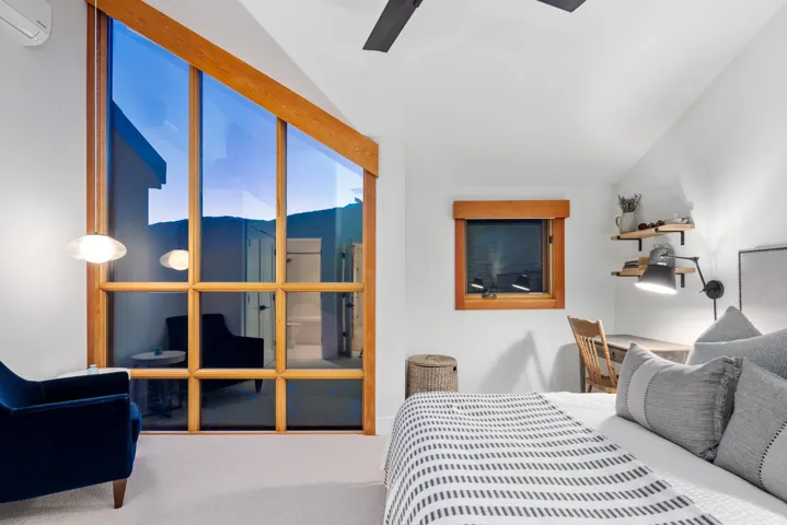Carpeted bedroom with ceiling fan, a wall unit AC, and vaulted ceiling