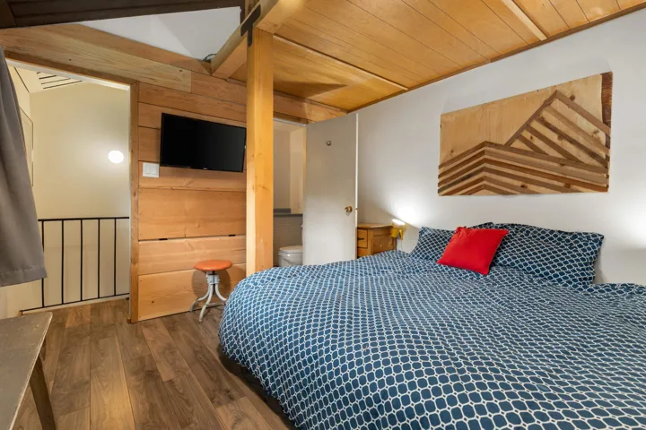 Bedroom with wood finished floors, wooden ceiling, ensuite bath, and wooden walls