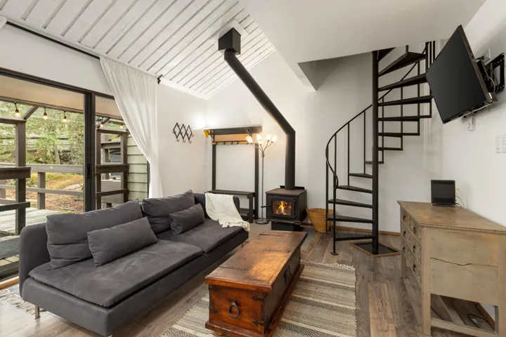Living room with a wood stove, stairway, dark wood-type flooring, and vaulted ceiling