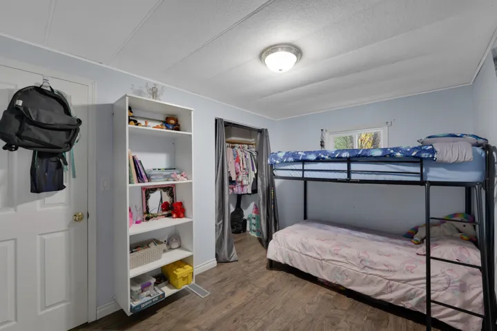 Bedroom with dark wood-type flooring, a closet, and a textured ceiling
