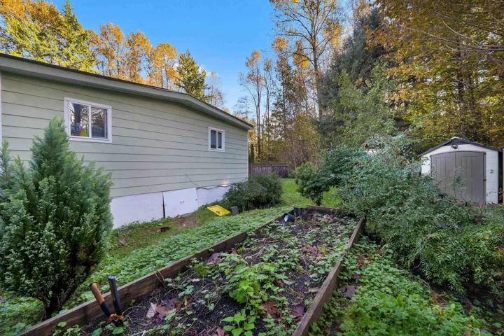 View of property exterior featuring a vegetable garden and a storage shed
