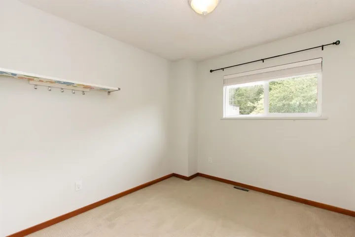 Carpeted spare room featuring baseboards