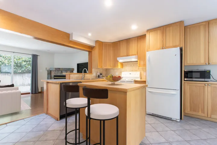 Kitchen featuring open floor plan, stainless steel appliances, a breakfast bar, light tile patterned floors, and recessed lighting