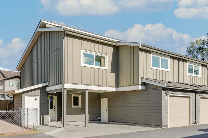Contemporary multi-level exterior featuring vertical and horizontal siding, multiple windows, an integrated carport, and an attached garage with a tan door