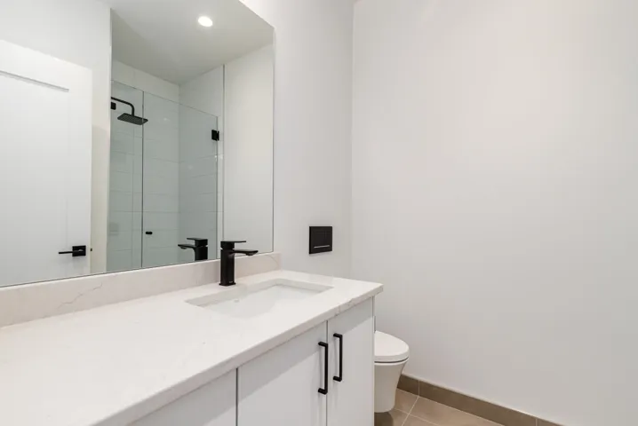 Bathroom with vanity, tile patterned flooring, tiled shower, and recessed lighting
