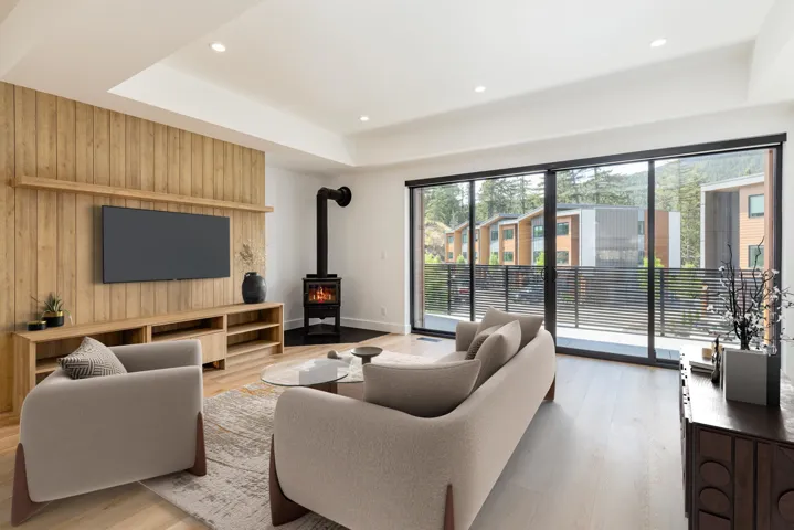 Living area featuring a wood stove, wooden walls, light wood-style floors, a tray ceiling, and recessed lighting
