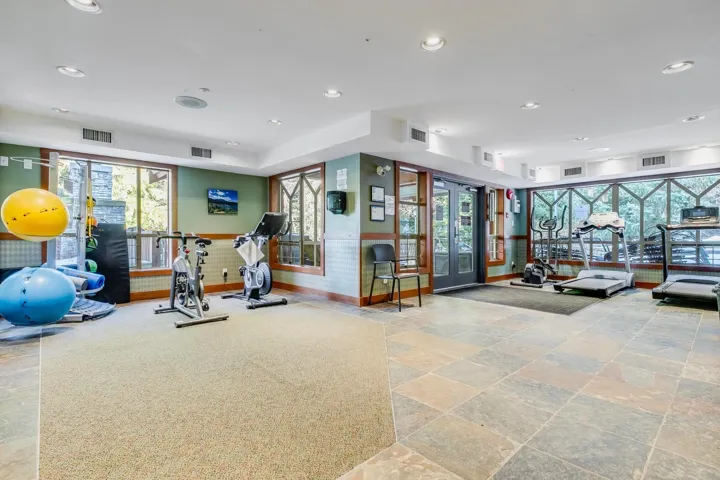 Gym featuring recessed lighting, plenty of natural light, wainscoting, and stone finish floors