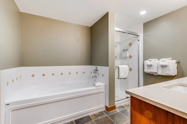 Bathroom featuring a garden tub, a shower stall, vanity, recessed lighting, and dark stone finish floors