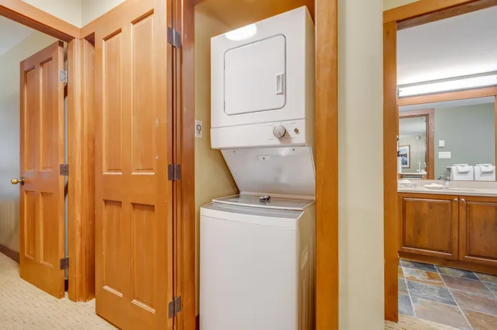 Laundry area with stacked washer / dryer and stone finish flooring