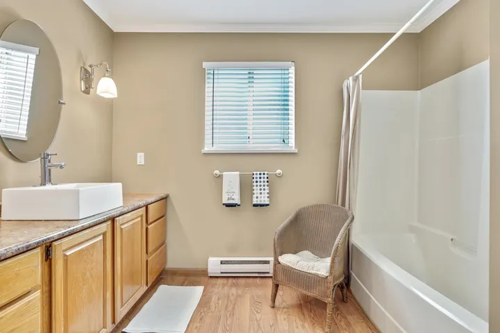 Full bathroom with wood finished floors, vanity and shower / bath combo