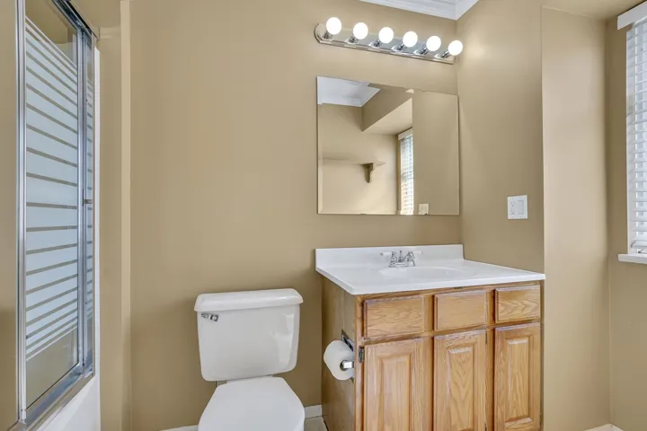 Full bath with crown molding, toilet, vanity, and a shower with shower door