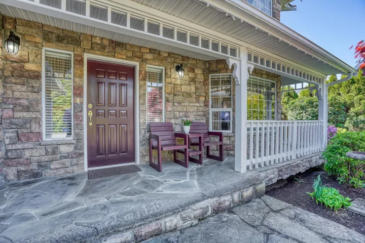 Property entrance featuring covered porch and stone siding