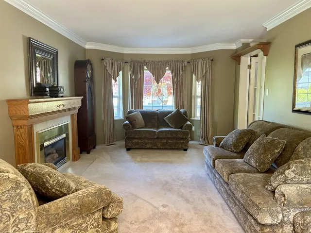 Living area with light carpet, ornamental molding, visible vents, and a tile fireplace