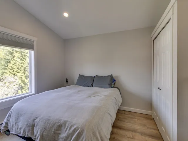 Bedroom featuring lofted ceiling, wood finished floors, multiple windows, and a closet