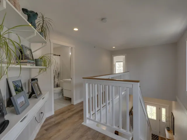 Hallway featuring baseboards, an upstairs landing, light wood-type flooring, and recessed lighting