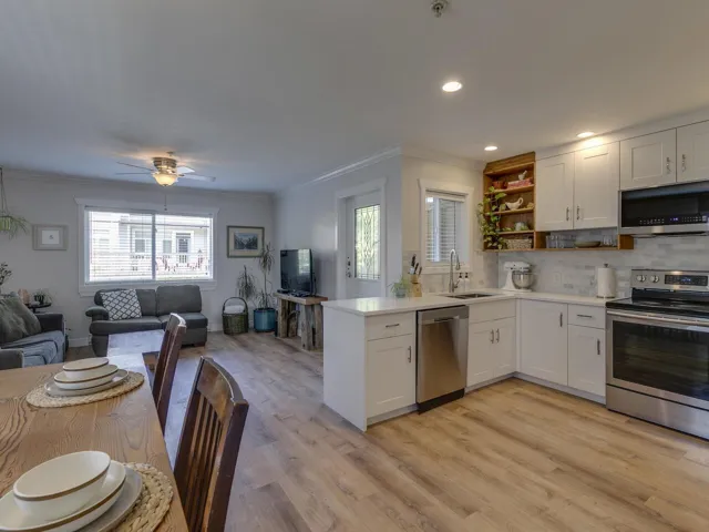 Kitchen featuring open shelves, a sink, open floor plan, appliances with stainless steel finishes, and ornamental molding