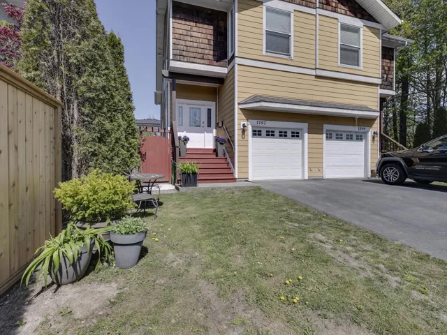 View of front facade with an attached garage, a balcony, a front yard, and aphalt driveway
