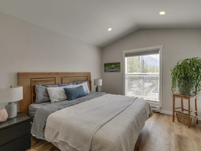 Bedroom featuring recessed lighting, vaulted ceiling, a baseboard heating unit, light wood-type flooring, and baseboards