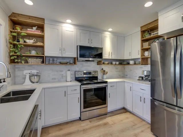 Kitchen featuring open shelves, stainless steel appliances, light countertops, and a sink