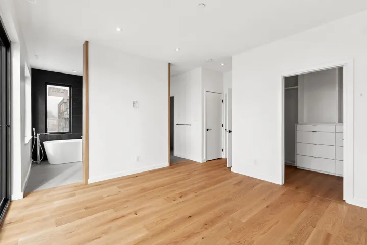 Unfurnished bedroom with a walk in closet, connected bathroom, light wood-style flooring, and baseboards