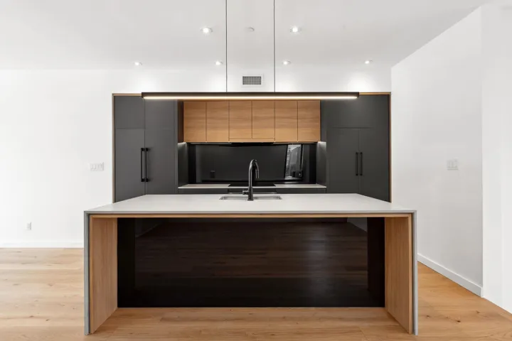 Kitchen featuring light countertops, visible vents, a large island with sink, and modern cabinets
