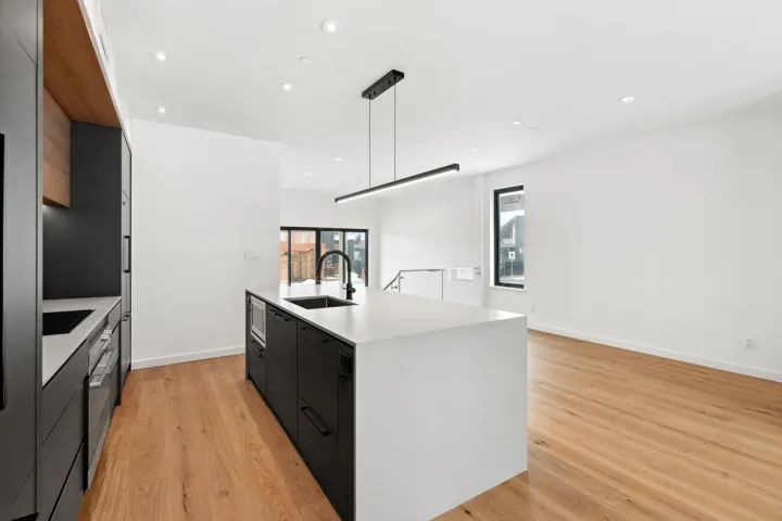 Kitchen with dark cabinets, a sink, light countertops, modern cabinets, and a center island with sink