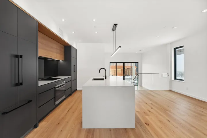 Kitchen with black electric stovetop, a sink, stainless steel oven, light countertops, and modern cabinets