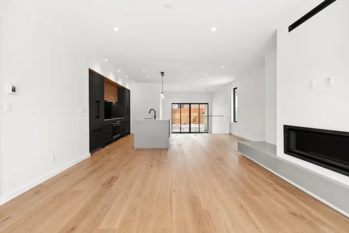 Unfurnished living room featuring baseboards, light wood finished floors, a sink, and recessed lighting