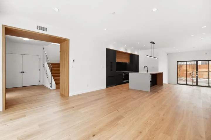 Unfurnished living room featuring visible vents, stairway, light wood-style floors, a sink, and recessed lighting