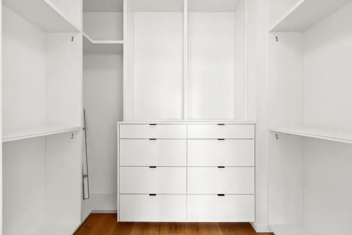 Walk in closet with dark wood-style floors