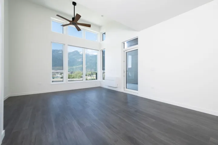 Unfurnished room featuring a ceiling fan, plenty of natural light, a mountain view, and dark wood-style flooring