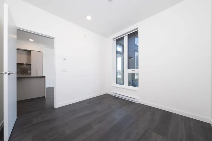 Empty room with dark wood-type flooring, a baseboard radiator, and recessed lighting