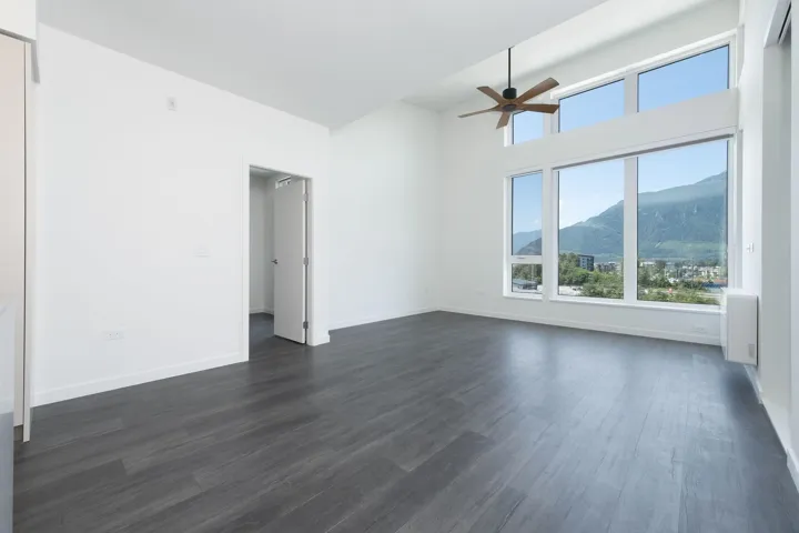 Empty room with a mountain view, healthy amount of natural light, a ceiling fan, and dark wood-type flooring