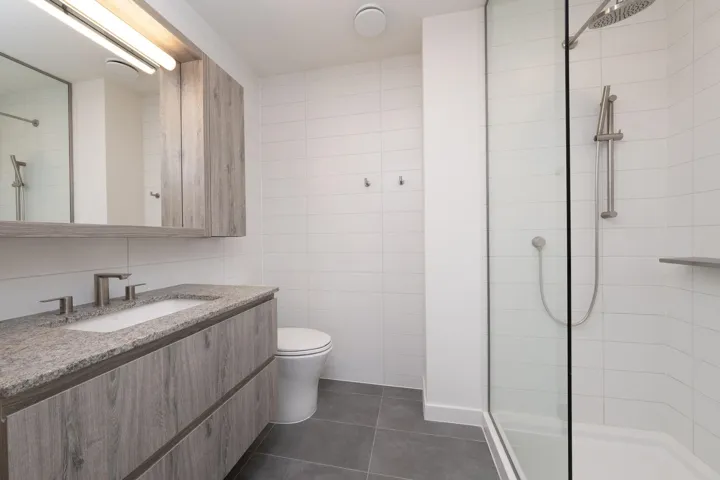 Bathroom featuring a tile shower, tile patterned flooring, vanity, and tile walls