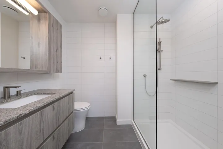 Full bath featuring tile patterned flooring, a tile shower, vanity, and tile walls