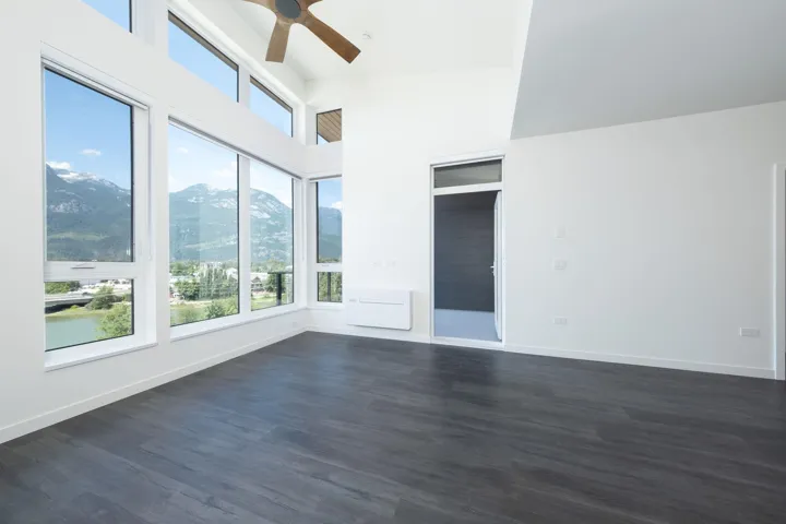 Empty room with healthy amount of natural light, ceiling fan, and dark wood-type flooring
