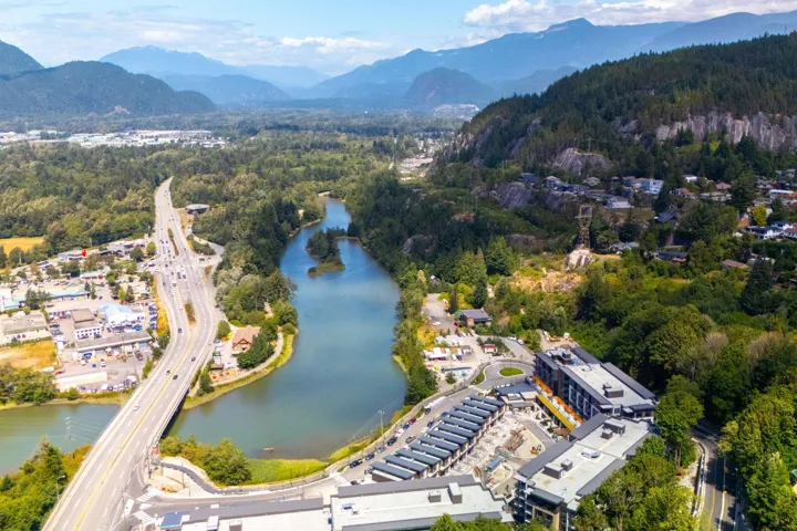 Aerial view of property and surrounding area with a heavily wooded area and a water and mountain view