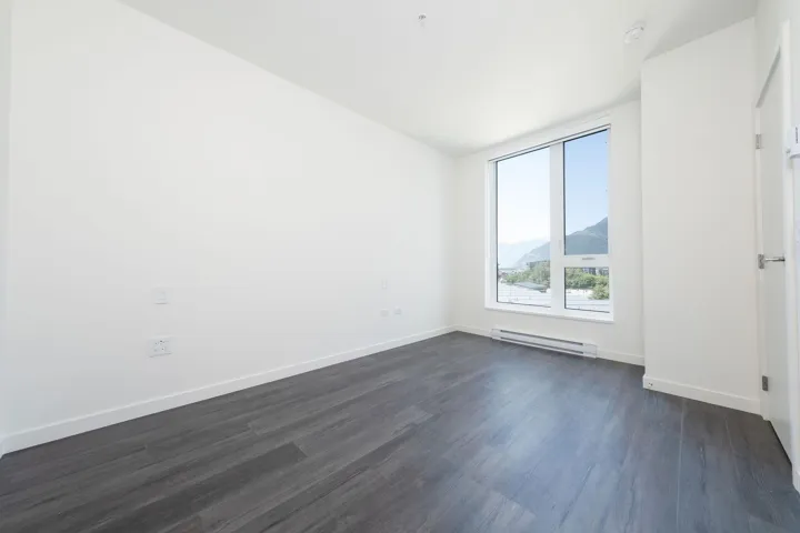 Empty room featuring dark wood-type flooring, a baseboard radiator, and a mountain view