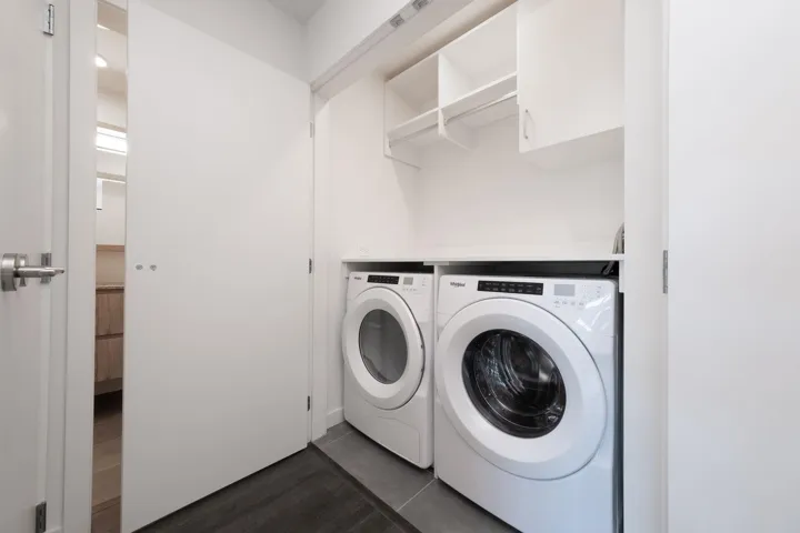 Washroom with separate washer and dryer, dark wood-style flooring, and cabinet space