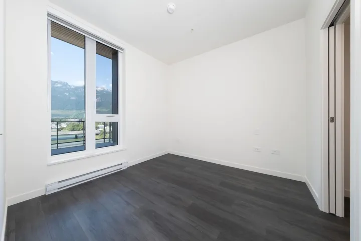 Unfurnished room featuring baseboard heating and dark wood-style flooring