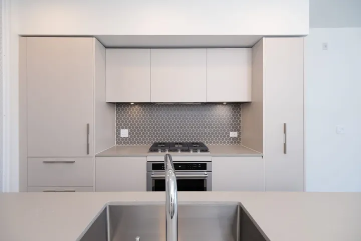 Kitchen featuring light countertops, backsplash, stainless steel appliances, white cabinetry, and modern cabinets