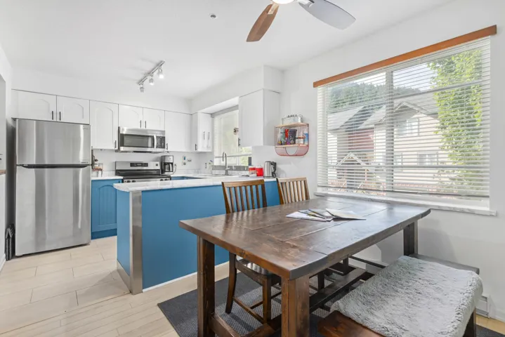 Kitchen featuring stainless steel appliances, white cabinets, light countertops, and ceiling fan