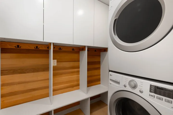 Washroom with stacked washer / dryer and wood finished floors