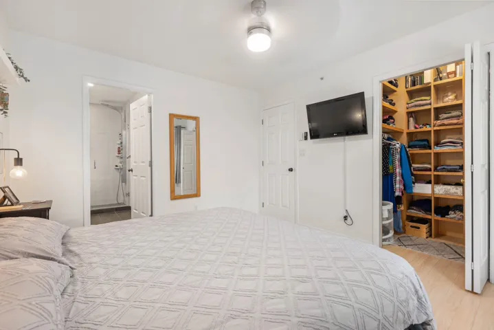 Bedroom featuring light wood-style flooring, a walk in closet, and connected bathroom
