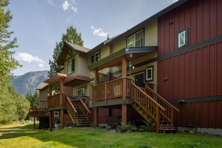 Back of property with stairs, board and batten siding, a deck with mountain view, and a lawn
