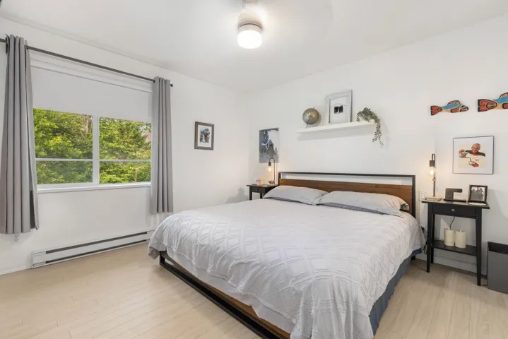 Bedroom with a baseboard heating unit and light wood-type flooring