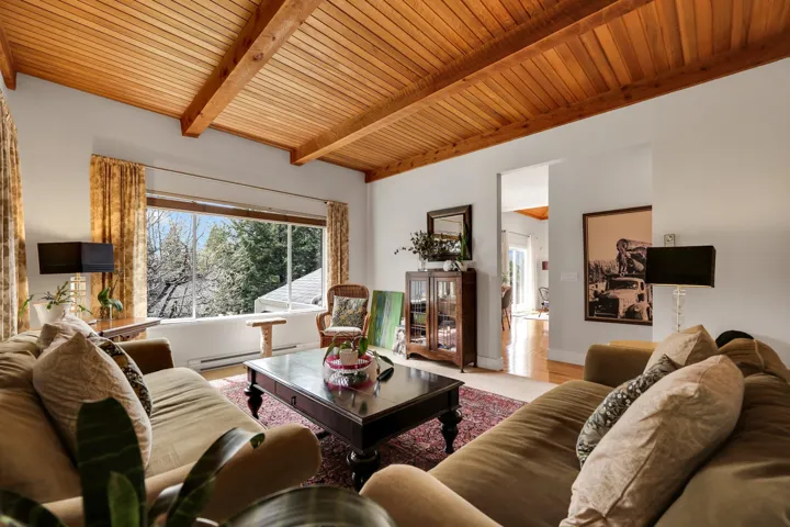 Living area featuring a wood ceiling with exposed beams and a baseboard heating unit