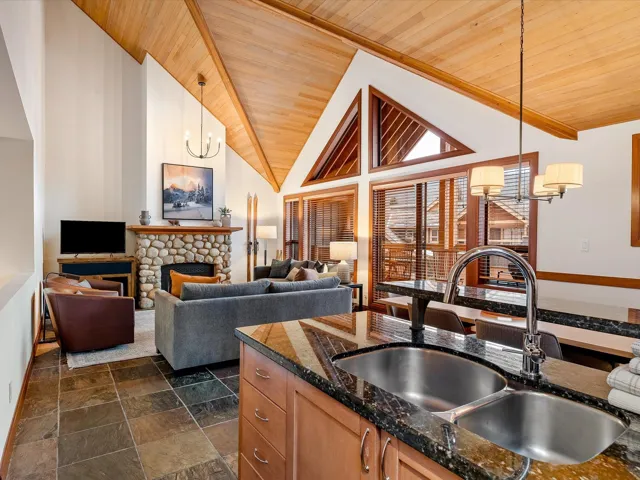 Kitchen featuring tasteful backsplash, baseboards, appliances with stainless steel finishes, dark stone countertops, and range hood