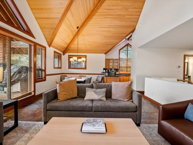 Living area with wooden ceiling, baseboards, high vaulted ceiling, and a notable chandelier